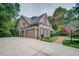 Elegant brick home featuring a three-car garage and a beautifully landscaped yard with mature trees at 9070 Huntcliff Trce, Sandy Springs, GA 30350