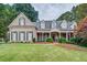 Beautiful brick home featuring a well-manicured lawn and a charming, covered front porch at 9070 Huntcliff Trce, Sandy Springs, GA 30350