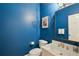 Stylish powder room with vibrant blue walls, gold fixtures, and classic accents at 835 Springside Ne Ct, Atlanta, GA 30342