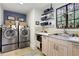 Well-organized laundry room featuring stainless steel washer/dryer, storage, and a sink under the window at 6 Arden Moor Nw, Atlanta, GA 30305