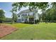 Spacious backyard of white house, showcasing a covered patio, fire pit area, and well-manicured lawn at 100 Chateau Pl, Woodstock, GA 30188