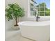 Close up of a freestanding tub with black fixtures under a bright window at 100 Chateau Pl, Woodstock, GA 30188