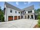 Expansive modern farmhouse with a three-car garage, large driveway, and inviting front porch at 100 Chateau Pl, Woodstock, GA 30188