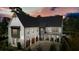 An exterior twilight view of the home with a charming front porch and 3-car garage at 100 Chateau Pl, Woodstock, GA 30188