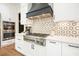 Gourmet kitchen featuring a stainless steel stove, designer backsplash, and custom range hood at 100 Chateau Pl, Woodstock, GA 30188