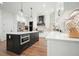 Modern kitchen boasts a dark island with marble countertops, white cabinets, and stainless steel appliances at 100 Chateau Pl, Woodstock, GA 30188