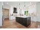 Spacious kitchen featuring a dark island, marble countertops, sleek black range hood, and white cabinetry at 100 Chateau Pl, Woodstock, GA 30188