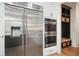 Kitchen boasts stainless steel refrigerator, double ovens, custom cabinetry, and adjacent mudroom at 100 Chateau Pl, Woodstock, GA 30188