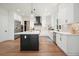 Well-lit kitchen with a dark island, marble countertops, stainless steel appliances, and modern white cabinets at 100 Chateau Pl, Woodstock, GA 30188