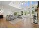 Open living room with a large gray sectional, fireplace, and a wall of windows overlooking the backyard at 100 Chateau Pl, Woodstock, GA 30188