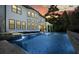 Exterior shot of a modern home with black frame windows, a pool, lounge chairs, and well-lit patio at 100 Chateau Pl, Woodstock, GA 30188