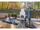 A backyard featuring a stone patio with a fireplace, seating area, and lush landscaping at 4070 Whitewater Creek Nw Rd, Atlanta, GA 30327