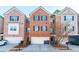 View of the brick townhome exterior with black shutters, a two car garage, landscaping, and a front door at 1605 Signal Flag Way, Lawrenceville, GA 30043