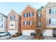 View of the brick townhome exterior with black shutters, a two car garage, landscaping, and a front door at 1605 Signal Flag Way, Lawrenceville, GA 30043