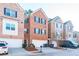 View of the brick townhome exterior with black shutters, a two car garage, landscaping, and a front door at 1605 Signal Flag Way, Lawrenceville, GA 30043