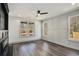 Open concept living room featuring hardwood floors, wainscoting, a ceiling fan and three large windows at 3900 Arbor Se Ln, Conyers, GA 30094