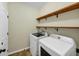 Bright laundry room features modern washer and dryer, and convenient wood shelving for storage at 275 Creek View Ln, Acworth, GA 30102