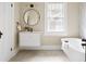 Bathroom with sleek white vanity, round mirror, soaking tub, and bright window at 536 Moreland Ne Ave, Atlanta, GA 30307