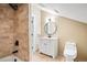 Modern bathroom with travertine tile shower, round mirror, and white vanity for a sleek design at 536 Moreland Ne Ave, Atlanta, GA 30307