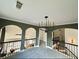 View of the second story hallway with arches, a large chandelier, and dark railings at 3390 Vista Creek Dr, Dacula, GA 30019