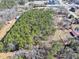 Expansive aerial view of a wooded lot with surrounding buildings and roads at 1891 Highway 81 E, Mcdonough, GA 30252