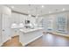 Modern white kitchen featuring a large island, stainless steel appliances, and natural light from the back door at 5707 Tillman Way, Powder Springs, GA 30127