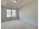 Bedroom with neutral carpet, a tray ceiling, and a window overlooking the neighborhood at 318 Delta Dr, Mcdonough, GA 30253