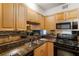 Galley kitchen featuring granite countertops, stainless steel sink, black appliances, and wood cabinets at 2479 Peachtree Ne Rd # 605, Atlanta, GA 30305