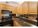 A galley kitchen features wood cabinets, granite countertops, stainless microwave and black oven at 2479 Peachtree Ne Rd # 605, Atlanta, GA 30305