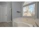 Relaxing bathroom featuring a soaking tub, tile floors, and a bright window at 54 Etham Pl, Douglasville, GA 30134
