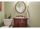 Well-lit powder room featuring a wooden vanity, round mirror, and neutral decor at 5216 Old Mountain Ln, Powder Springs, GA 30127