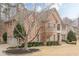 Brick home with a manicured lawn, decorative shrubbery, and a view of the three-car garage on the left at 5216 Old Mountain Ln, Powder Springs, GA 30127