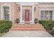 Elegant brick entryway leading to a decorative front door flanked by manicured shrubbery and classic sconces at 5216 Old Mountain Ln, Powder Springs, GA 30127