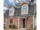 Charming brick townhome featuring a black front door, dormer windows, and mature landscaping at 8690 Ashley Way, Douglasville, GA 30134