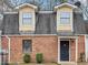 Charming brick townhome featuring a black front door, dormer windows, and mature landscaping at 8690 Ashley Way, Douglasville, GA 30134