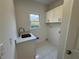 Bright laundry room features a sink, granite countertops, tile flooring, and natural light from a window at 9240 Prestwick Club Dr, Duluth, GA 30097