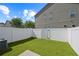 Fenced in backyard with well manicured fake grass and the side of a building at 2657 Avanti Way, Decatur, GA 30035