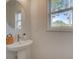 Stylish powder room with pedestal sink, round mirror, and window at 107 Winsome Way, Woodstock, GA 30188