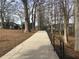 Concrete sidewalk with black metal railing lined with mature trees and foliage at 107 Winsome Way, Woodstock, GA 30188