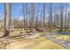 Spacious backyard has a scenic creek view, fire pit, Adirondack chairs and path with landscape lighting at 775 River Cliff Ct, Suwanee, GA 30024