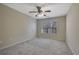 A well-lit bedroom featuring plush carpeting, a ceiling fan and a large window with natural light at 55 Burns View Ct, Lawrenceville, GA 30044