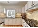 Traditional kitchen with white cabinets, black countertops, stainless steel appliances and natural backsplash at 976 Forest Pond Cir, Marietta, GA 30068