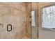 Stylish tiled shower featuring glass door, bronze fixtures, and window at 976 Forest Pond Cir, Marietta, GA 30068