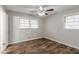 Well-lit bedroom with a ceiling fan and two windows showcasing the beautiful wood-look laminate flooring at 2600 Burkshire Rd, Ellenwood, GA 30294