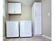 Tidy laundry area features sleek, front-load appliances, tile floor and white cabinets at 866 Lee Byrd Rd, Loganville, GA 30052