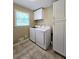 Well-lit laundry room boasts white cabinetry, tile floor, and modern washer and dryer at 866 Lee Byrd Rd, Loganville, GA 30052