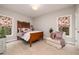 Cozy bedroom with a wooden bed frame, carpet flooring, accent chair, and windows with decorative floral curtains at 201 Russell Ct, Canton, GA 30115