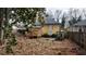 View of the backyard and yellow home with small deck and overgrown landscaping at 3033 Semmes St, Atlanta, GA 30344