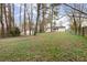 A view of the expansive, grassy backyard featuring mature trees and a view of the home at 3753 Adamsville Sw Dr, Atlanta, GA 30331