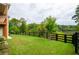Green backyard featuring a well-maintained lawn with a wooden fence and scenic views of lush greenery and a nearby lake at 4380 Serenity Lake Dr, Cumming, GA 30028